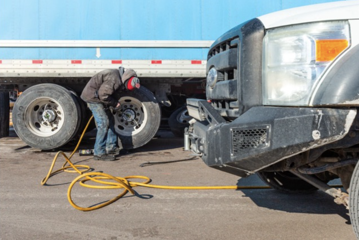 Technician repairing a commercial truck tire on the roadside